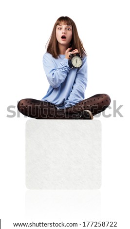worried young woman with an alarm clock sitting on a white box