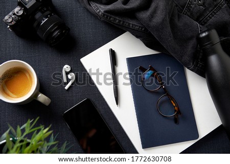 Flat Lay Lifestyle Shot With Camera Jacket Notebook Mobile Phone And Earphones On Black Background