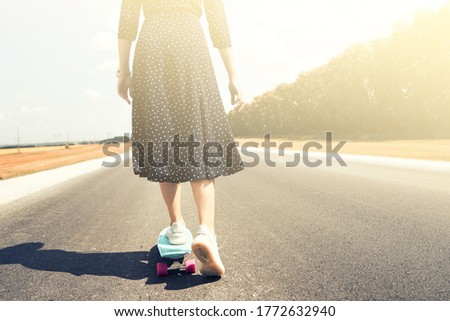 girl in black dress skates on hot summer road