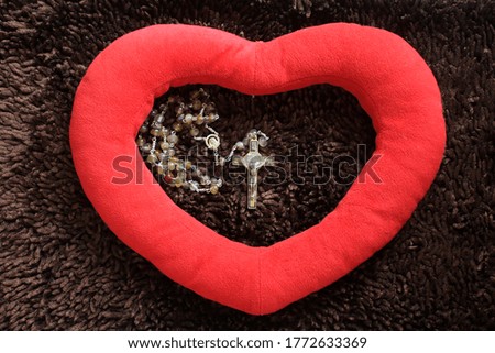 Heart love shape on brown background with rosary beads and Jesus Christ holy cross crucifix inside the heart. Love, pray and hope concept with rosary beads, the Catholic symbol. Top view.