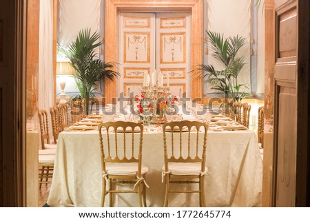 Vintage room with a long table with plates and glasses before the dinner
