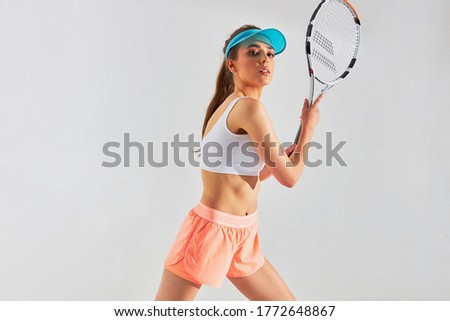 portrait photo of a beautiful sporty girl in in a uniform for playing tennis, posing with a racket on a white background