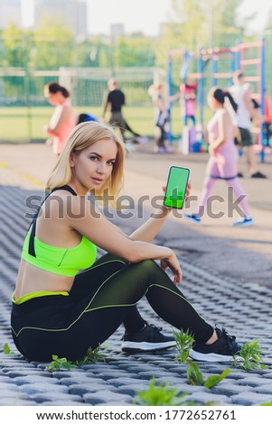 Tired fitness woman after workout and use smartphone with green screen.