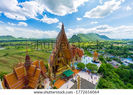 A view from the top of the pagoda, golden buddha statue with rice fields and mountain, Tiger Cave Temple (Wat Tham Seua) Thai and Chinese temples in Kanchanaburi province.