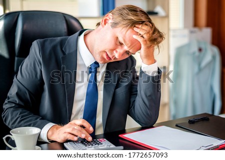 Stressed businessman worry about financial balance trouble of his company at his office in the morning. Profit less than target while global corona virus or Covid-19 crisis, negative emotional concept