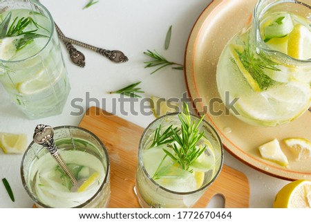 Refreshing iced drink with lemon and fresh rosemary, detox summertime
