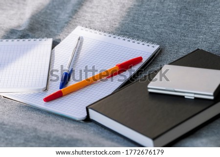 Office on a gray fabric background. Pens, various notebooks, a daily planner, a business card holder. A set of accessories for business and study. School supplies. Student's belongings. The office set