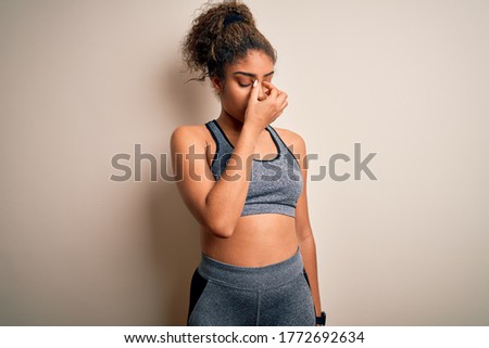 Young african american sportswoman doing sport wearing sportswear over white background tired rubbing nose and eyes feeling fatigue and headache. Stress and frustration concept.