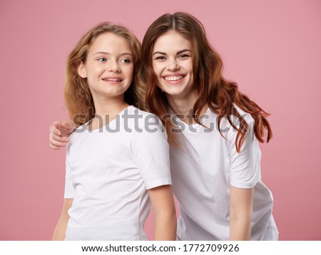 Beautiful woman and little girl rise on a pink background family 