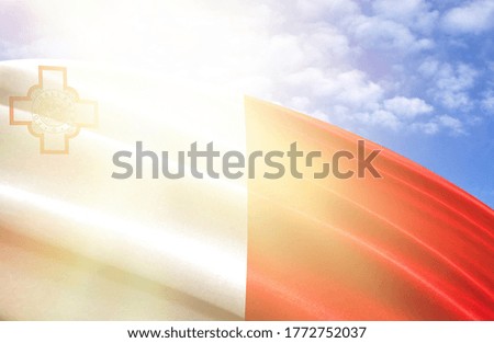 flag of Malta against the blue sky with sun rays