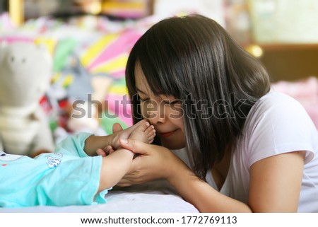 Mother holding infant's legs and kissing her baby's feet. 