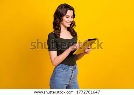 Profile side view portrait of her she nice attractive smart clever cheerful cheery wavy-haired girl holding in hands ebook studying web isolated on bright vivid shine vibrant yellow color background