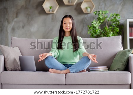 Full size photo of focused calm korean girl sit couch legs crossed folded barefoot meditate work study break pause in house indoors