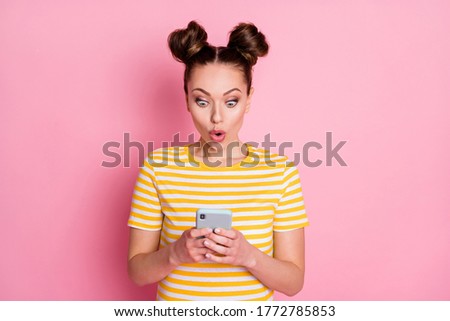 Photo of attractive lady two funny buns hold telephone blog post read news information open mouth crazy wear casual white yellow striped t-shirt isolated pink color background