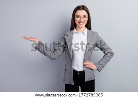 Photo of attractive business lady worker hold open arm empty space showing novelty sale price product wear specs shirt plaid blazer isolated grey color background