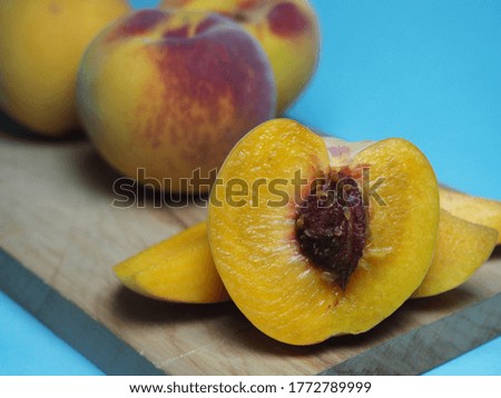 whole and poached peaches on a kitchen board on a pastel background with selective focus