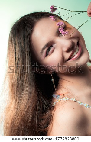 Smiling Beauty portrait of a young blonde girl wearing makeup with pink flower