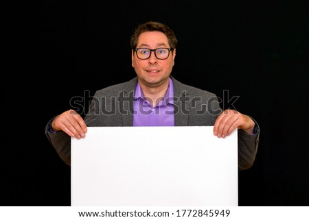 Front view image of calm caucasian Business man holding a blank banner isolated on black studio background