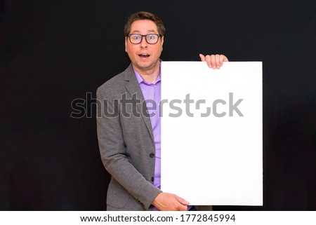 Front view image of caucasian Business man holding a blank banner isolated on black studio background