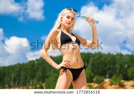 portrait of a young beautiful blonde girl in black bikini