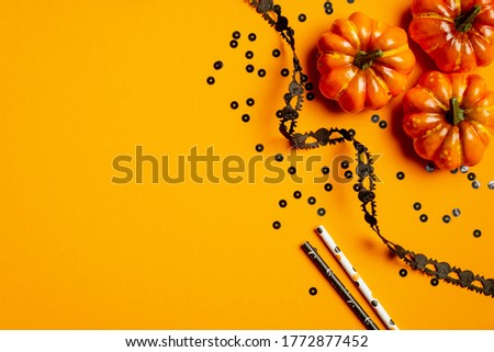 Halloween party decorations and pumpkins on orange background. Flat lay, top view. Happy halloween greeting card mockup.