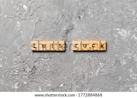 Let's Rock word written on wood block. Lets Rock text on cement table for your desing, concept.