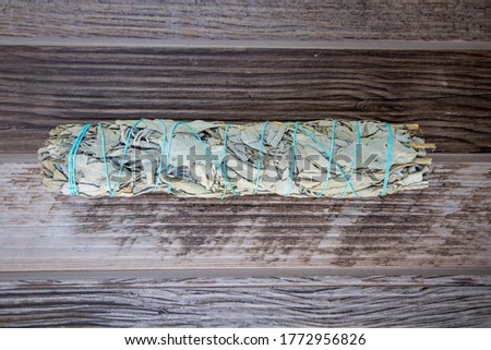 Bundle of White Sage tied with blue thread on wood background