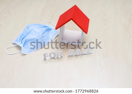 Front view of block letters on for sale, a toy house and surgical face mask on wooden table 