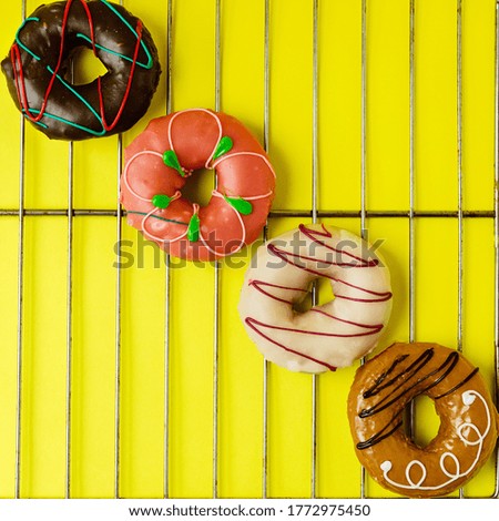colored glazed doughnuts on a grid and a bright yellow background. the concept of fresh, delicious and beautiful baking.