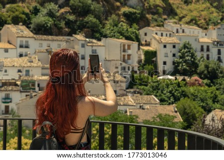 Tourist girl taking picture with phone with amazing landscape of rural town in Spain