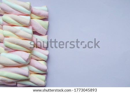 Close up picture of marshmallow in pastel shades on left side on light lavender background. Copy space concept with unhealthy sweets with amount of calories and sugar. Flat lay composition.
