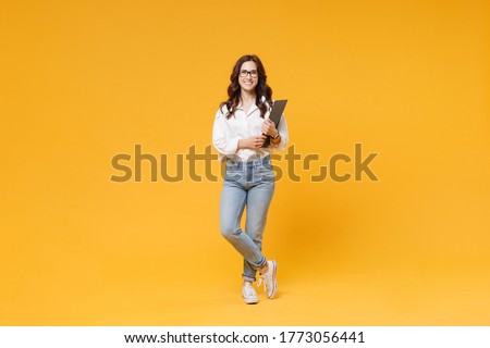 Full length of smiling young business woman in white shirt glasses isolated on yellow background studio. Achievement career wealth business concept. Mock up copy space. Hold clipboard papers document Royalty-Free Stock Photo #1773056441