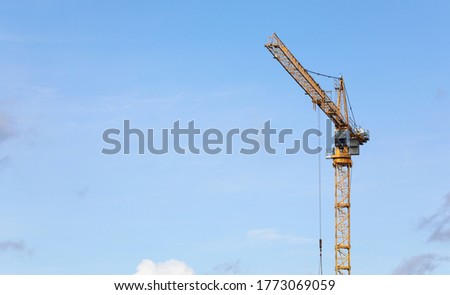 Close-up of yellow mobile tower crane on industrial construction site. Large tall machine used for moving heavy objects. Building complex and new project concept