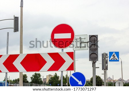Red and white Do not enter and other signs on gray dull overcast sky background