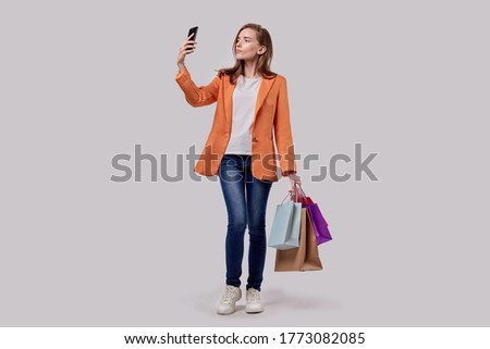 Satisfied girl takes a selfie with purchases in her hands. Online shopping.