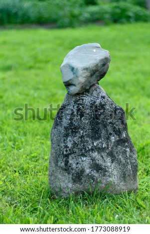 a stone figure stands on the grass