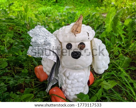 old and plastic toy in the form of a white poodle on the grass