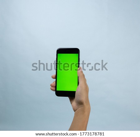 woman hand holding smarthphone on blue background with chroma key for use in projects or product placement