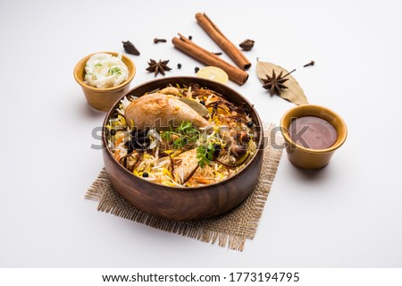 Restaurant style Spicy Chicken Biryani in wooden bowl with Raita and salan, Popular Indian or Pakistani Food Royalty-Free Stock Photo #1773194795