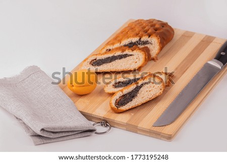 Strudel with poppy seeds on a wooden Board with a knife. Dessert poppy seed roll.