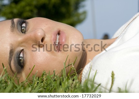 Close-up of a female wearing a white top laying in the grass on a sunny day