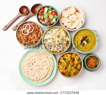 Indian whole vegetarian meal with yellow dal, vegetable pulao, chapati,gulab jamun, salad, papad, pickle, chana masala curry and aloo gobi Royalty-Free Stock Photo #1773227648
