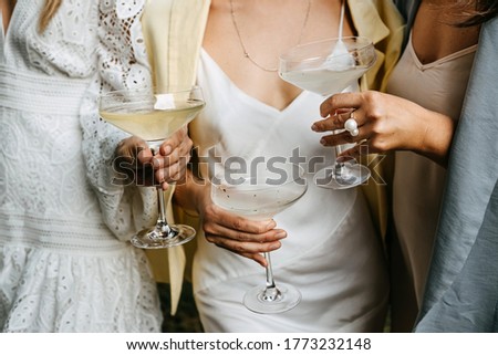 Women wearing summer dresses, holding glasses of champagne at a party. Royalty-Free Stock Photo #1773232148