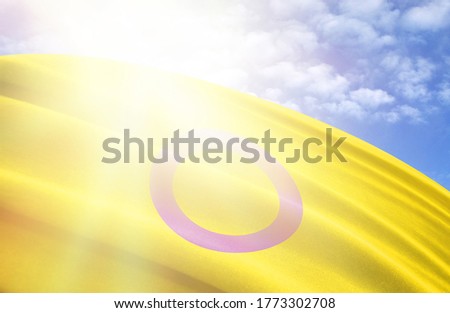 flag of intersex pride against the blue sky with sun rays