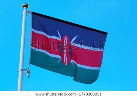 Large flag of KENYA waving in the wind with a blue sky background