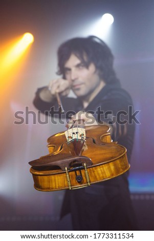 Violinist a player with a violin instrument in his hands. Artist of classical music or alternative music direction. Concept of stage art and performance.