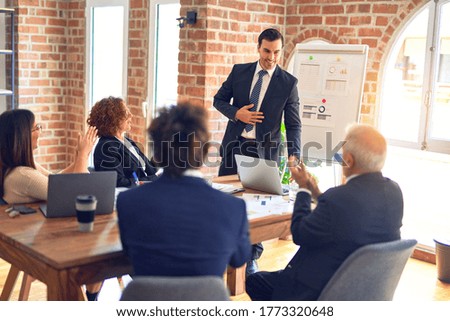 Group of business workers smiling happy and confident in a meeting. Working together looking at presentation using board and charts at the office.