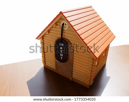a miniature replica of a country log house on a table with a white background behind it and a sign attached that reads " for rent"