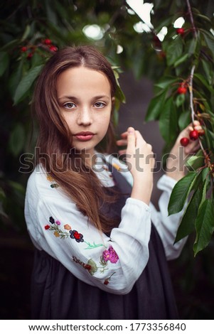 
 girl stands and picks cherries from a tree