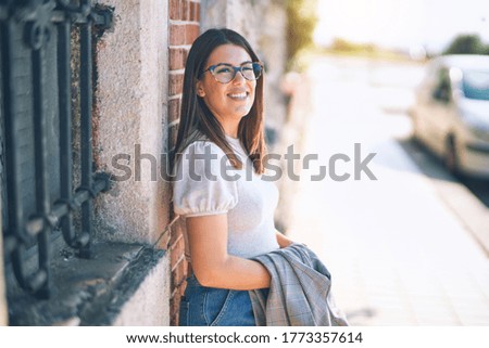 Young beautiful woman smiling happy and confident. Standing with smile on face leaning on the wall at the town street